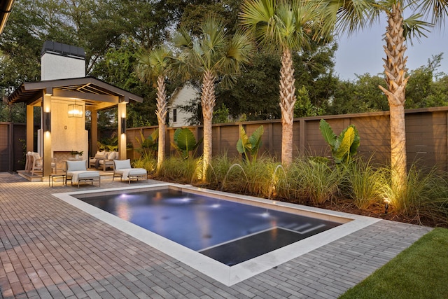 view of pool featuring an outdoor living space with a fireplace and a patio area