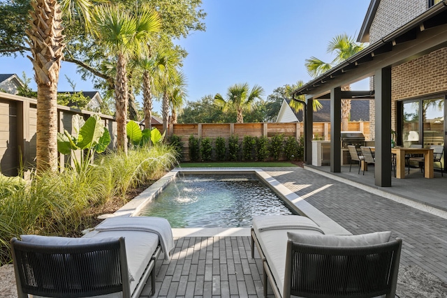 view of pool featuring a patio, pool water feature, and grilling area