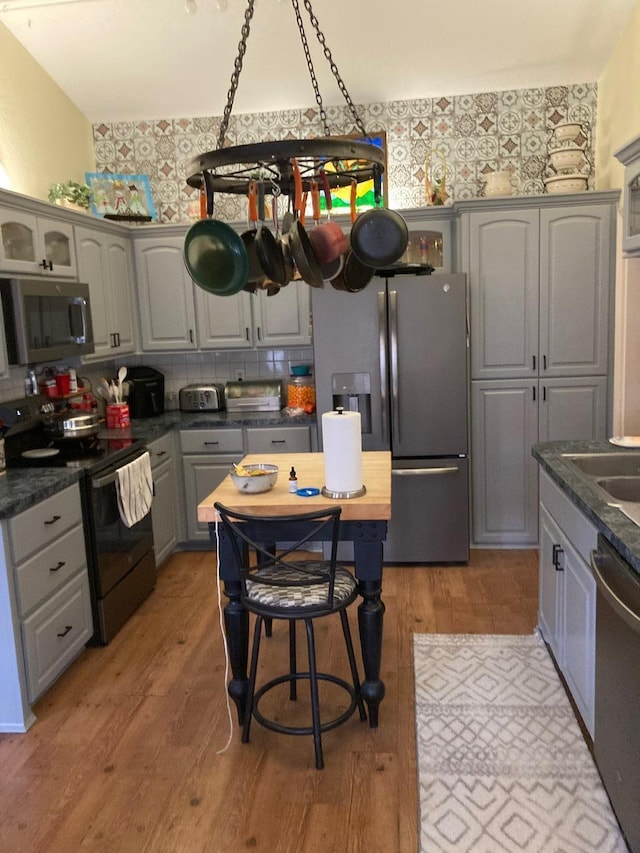 kitchen featuring gray cabinets, stainless steel appliances, decorative backsplash, and wood-type flooring