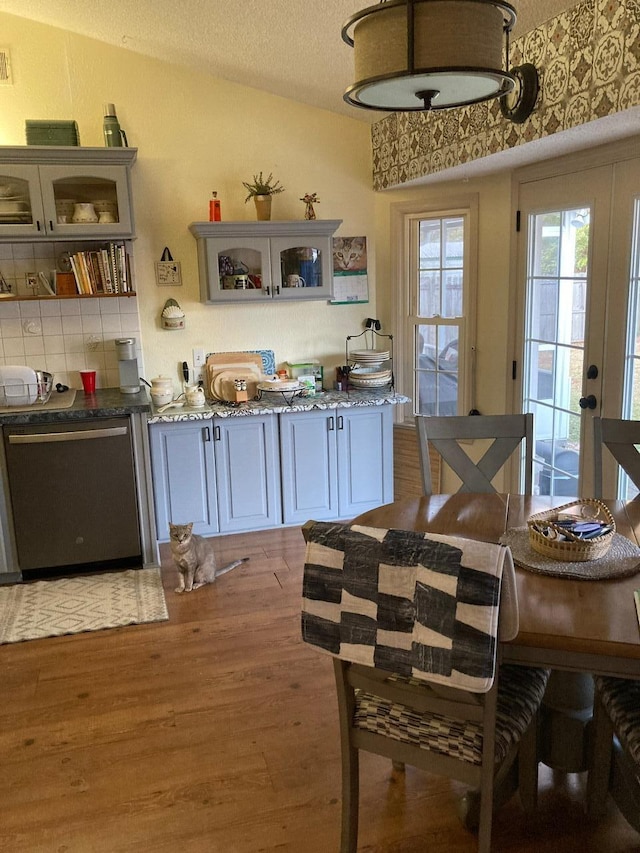 kitchen featuring dark stone countertops, hardwood / wood-style flooring, stainless steel dishwasher, and decorative backsplash