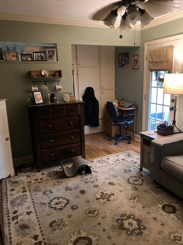 interior space with ceiling fan, light hardwood / wood-style flooring, crown molding, and a closet