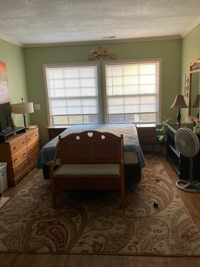 bedroom featuring a textured ceiling, ornamental molding, and hardwood / wood-style flooring