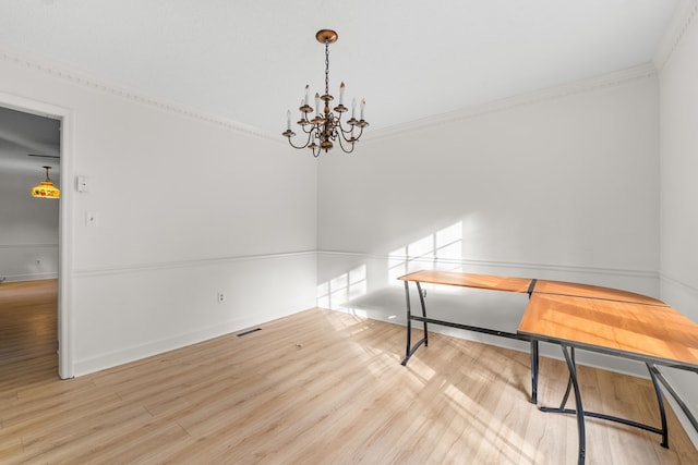 dining area featuring ornamental molding, an inviting chandelier, and light hardwood / wood-style floors