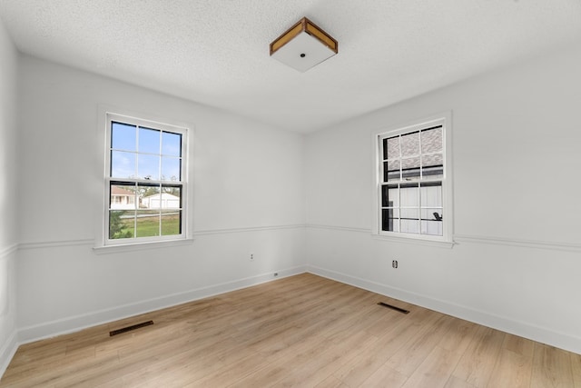 unfurnished room featuring a textured ceiling and light wood-type flooring