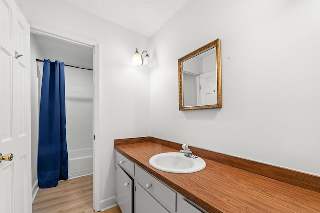 bathroom with hardwood / wood-style floors, vanity, and a textured ceiling