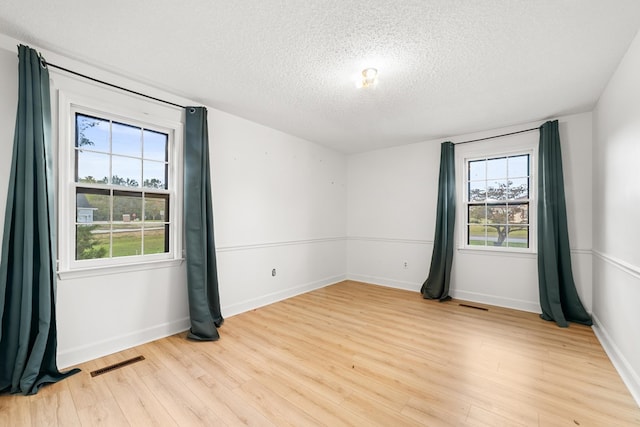 empty room with light hardwood / wood-style flooring and a textured ceiling