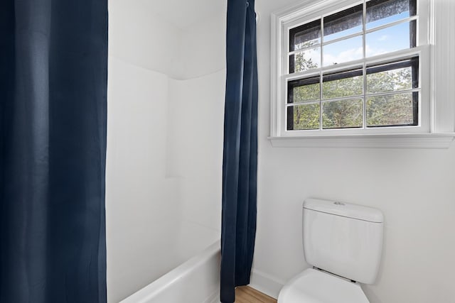 bathroom featuring hardwood / wood-style flooring, toilet, and shower / bathtub combination with curtain