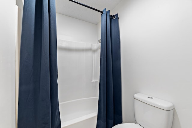 bathroom featuring shower / bath combo with shower curtain, toilet, and a textured ceiling