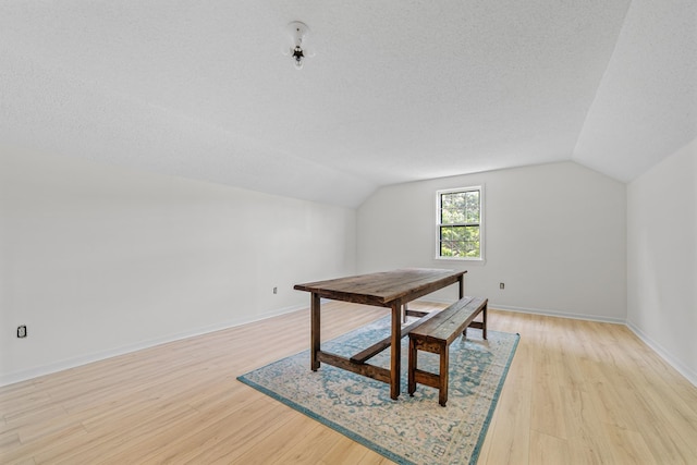 interior space with vaulted ceiling, light hardwood / wood-style floors, and a textured ceiling