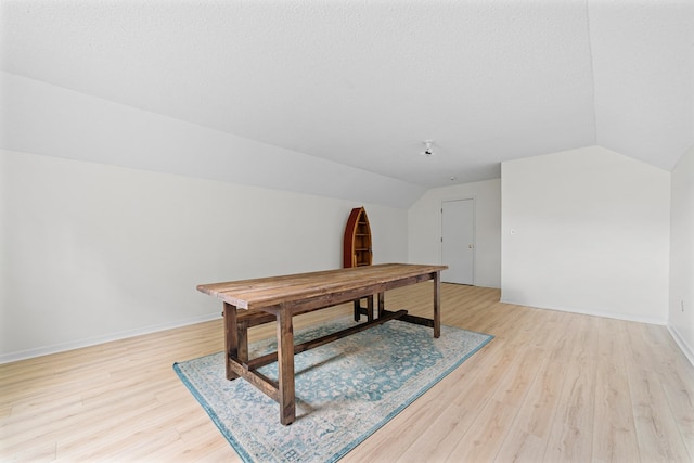 office area featuring vaulted ceiling, light hardwood / wood-style floors, and a textured ceiling