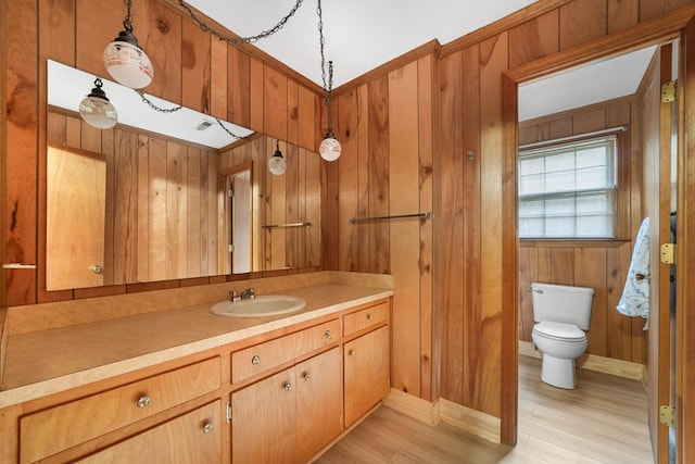 bathroom featuring wood walls, hardwood / wood-style flooring, vanity, and toilet