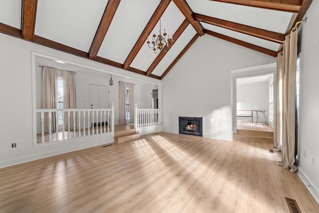 unfurnished living room featuring beamed ceiling, light hardwood / wood-style flooring, a chandelier, and high vaulted ceiling