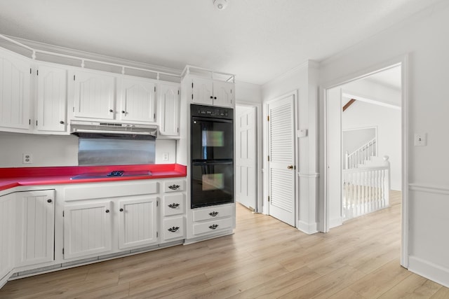 kitchen featuring white cabinets, crown molding, light hardwood / wood-style floors, and black appliances