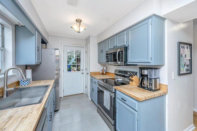 kitchen with appliances with stainless steel finishes, sink, and butcher block countertops