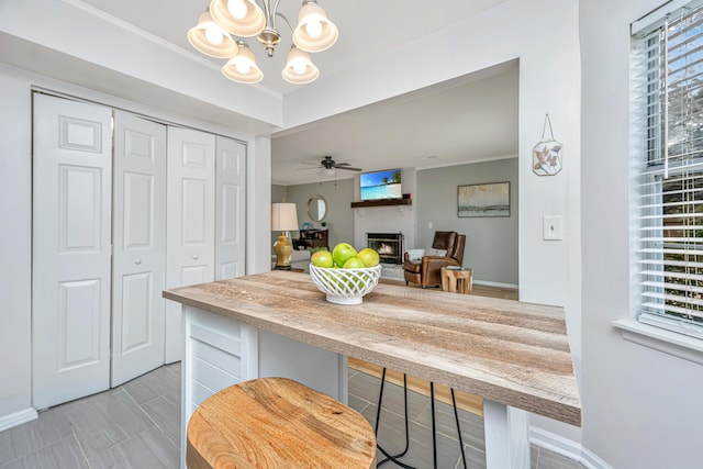 kitchen featuring crown molding, a healthy amount of sunlight, a breakfast bar, and ceiling fan with notable chandelier