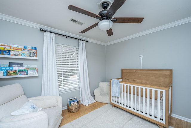 bedroom featuring crown molding, wood-type flooring, and a crib