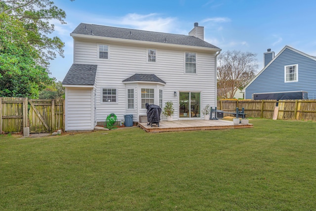 rear view of house featuring a wooden deck and a yard