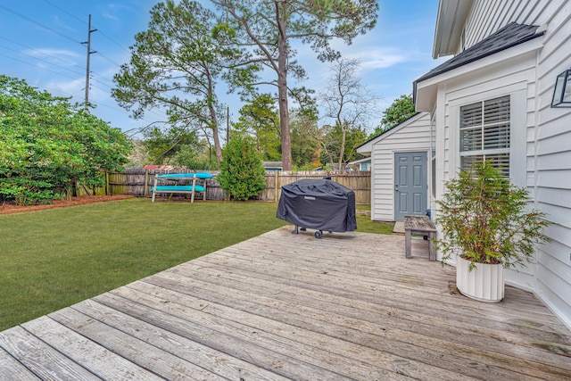 deck with a grill, a yard, and a trampoline