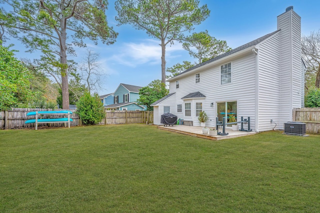 rear view of property featuring central AC, a yard, and a trampoline