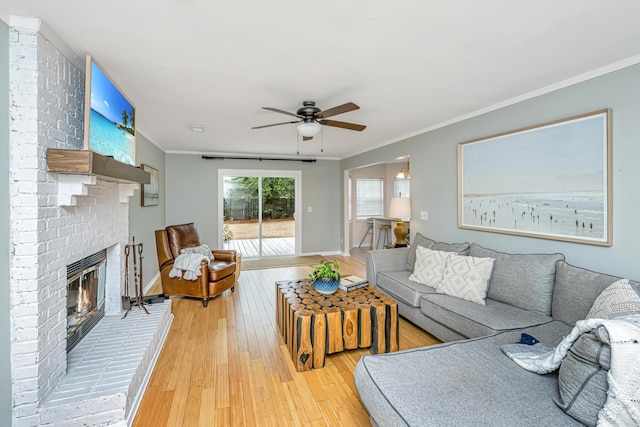 living room with hardwood / wood-style flooring, ceiling fan, ornamental molding, and a fireplace