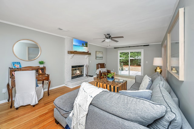 living room featuring crown molding, ceiling fan, hardwood / wood-style floors, and a brick fireplace