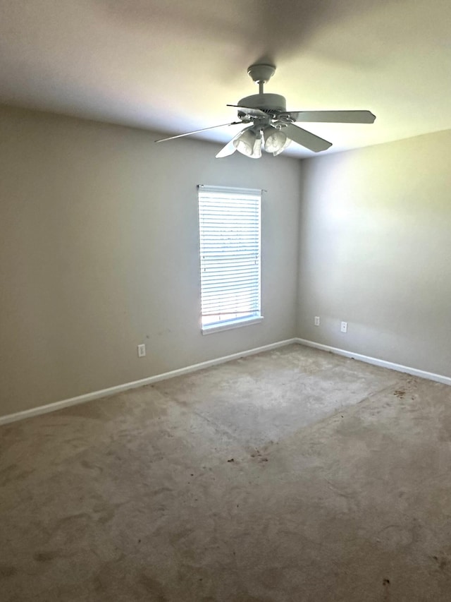 carpeted empty room with ceiling fan and baseboards