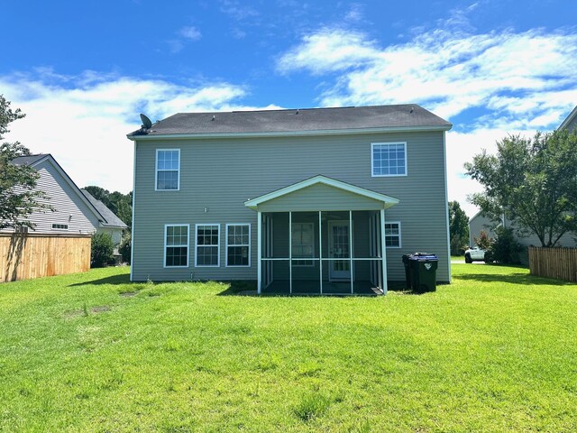 rear view of house featuring a sunroom and a lawn