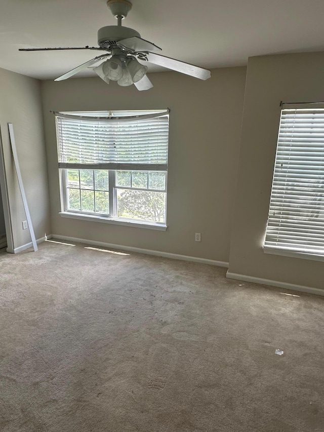 empty room with baseboards, a ceiling fan, and light colored carpet