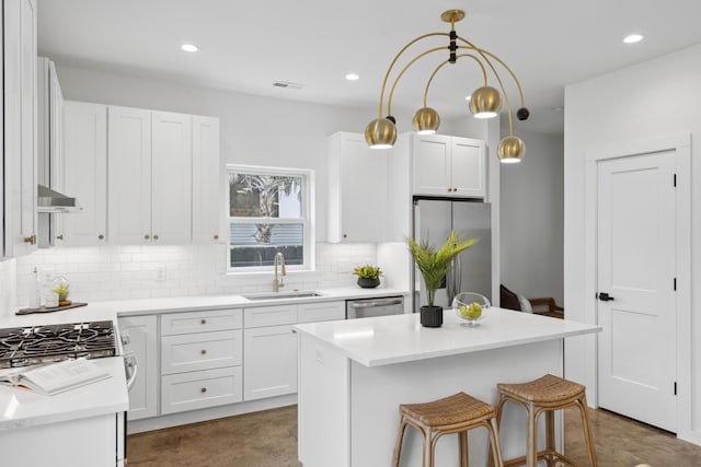 42 Poinsett St Unit B, Charleston, SC 29403 - kitchen featuring a sink, appliances with stainless steel finishes, decorative backsplash, white cabinets, and a kitchen bar