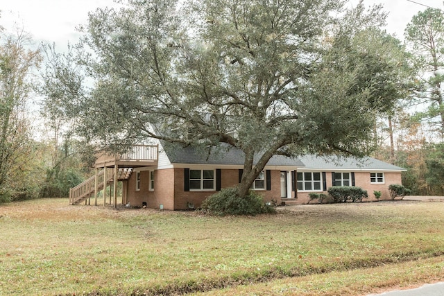 ranch-style home with a wooden deck and a front lawn