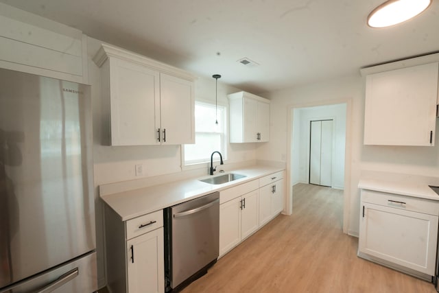 kitchen with white cabinets, decorative light fixtures, stainless steel appliances, and sink