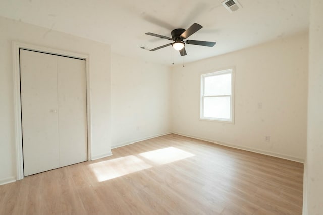 unfurnished bedroom with ceiling fan, a closet, and light hardwood / wood-style flooring