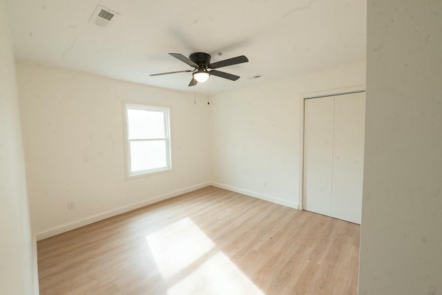 unfurnished bedroom featuring ceiling fan, a closet, and light wood-type flooring