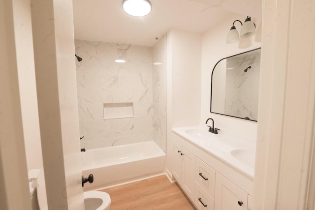 full bathroom featuring hardwood / wood-style floors, vanity, toilet, and tiled shower / bath