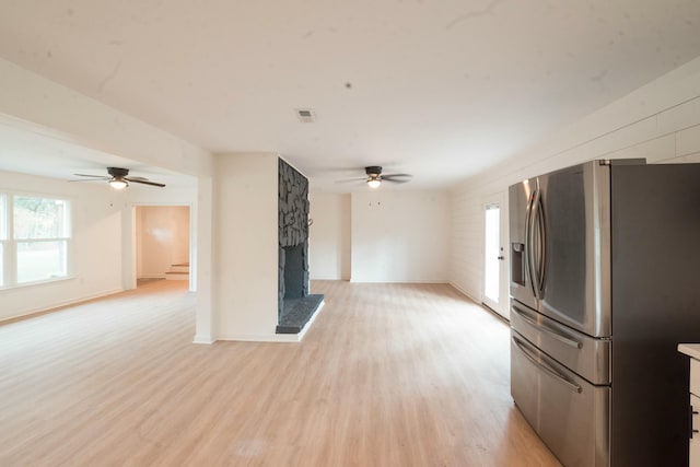 unfurnished living room with a stone fireplace, ceiling fan, and light hardwood / wood-style flooring