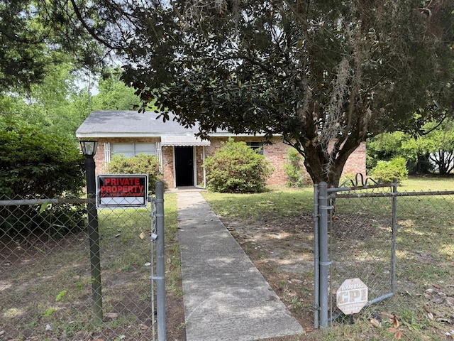 view of front of house with fence private yard, brick siding, a front yard, and a gate