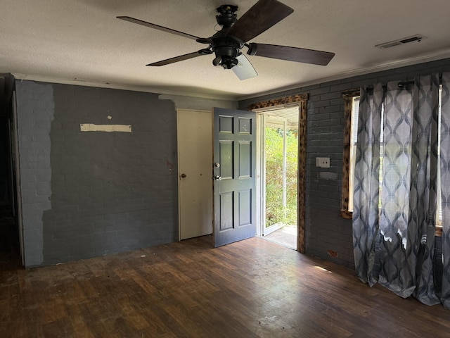 foyer entrance featuring ceiling fan, wood finished floors, brick wall, and visible vents