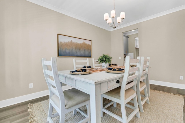 dining area featuring wood-type flooring, ornamental molding, and an inviting chandelier