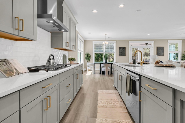 kitchen featuring gray cabinets, light wood-type flooring, pendant lighting, wall chimney range hood, and stainless steel appliances