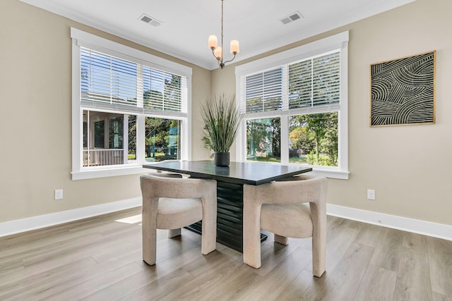 dining area featuring a notable chandelier, light hardwood / wood-style flooring, and crown molding