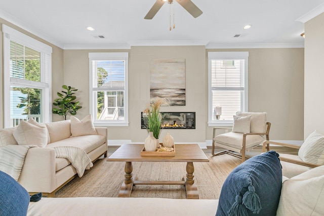 living room with ceiling fan, light wood-type flooring, crown molding, and a wealth of natural light