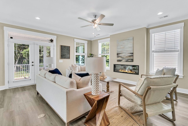 living room with ceiling fan, light wood-type flooring, and ornamental molding