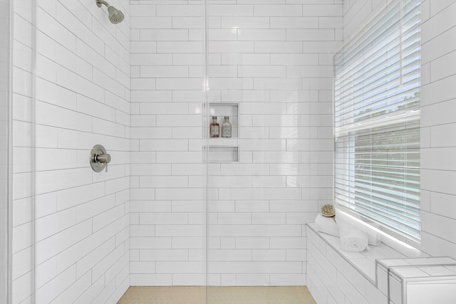 bathroom with a healthy amount of sunlight and tiled shower