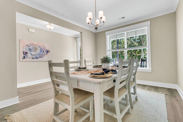 dining area with an inviting chandelier, hardwood / wood-style flooring, and ornamental molding