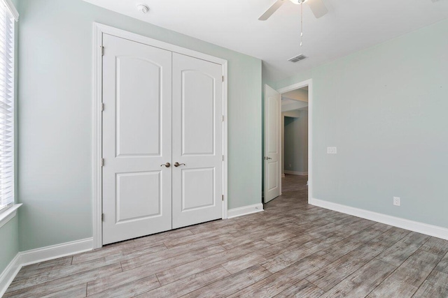 unfurnished bedroom featuring multiple windows, a closet, ceiling fan, and light wood-type flooring