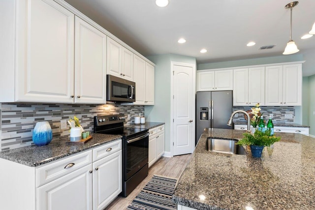 kitchen featuring dark stone counters, stainless steel appliances, white cabinetry, and decorative light fixtures