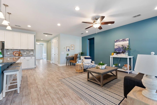 living room with ceiling fan and light hardwood / wood-style flooring