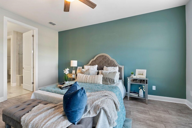 bedroom featuring ceiling fan, light hardwood / wood-style floors, and ensuite bath