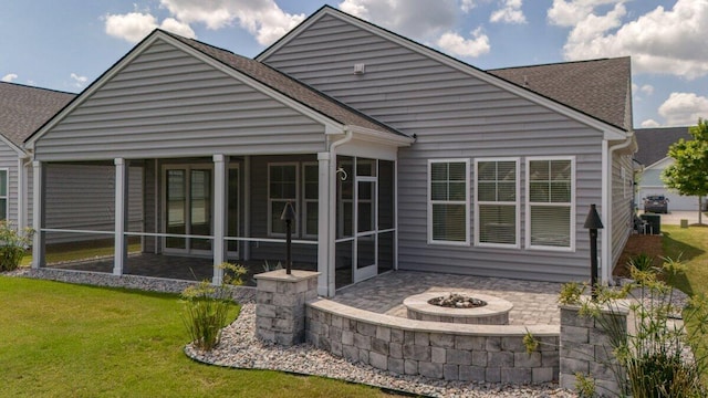 rear view of property with a fire pit, a sunroom, and a yard