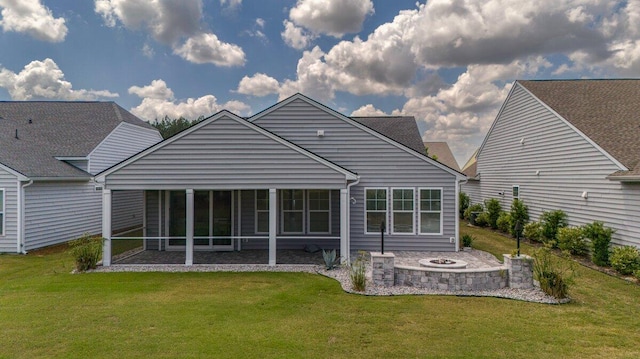 back of property with a sunroom, a yard, and a fire pit